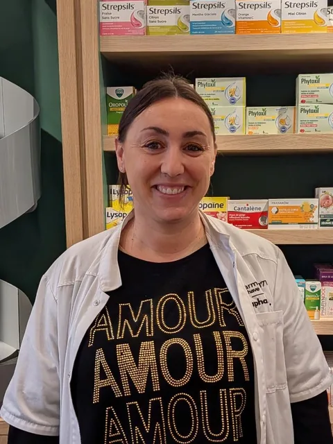 Magali, préparatrice en pharmacie, souriante devant les étagères